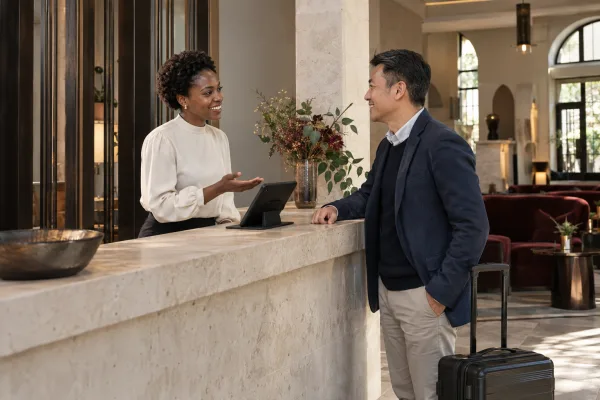 Rezeptionistin begrüßt einen Gast an einer Hotelrezeption